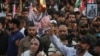 A demonstrator burns a printout of U.S. President Joe Biden, as supporters of Iraqi Shiite armed groups gather to protest against the U.S. for supporting Israel, Oct. 20, 2023. 