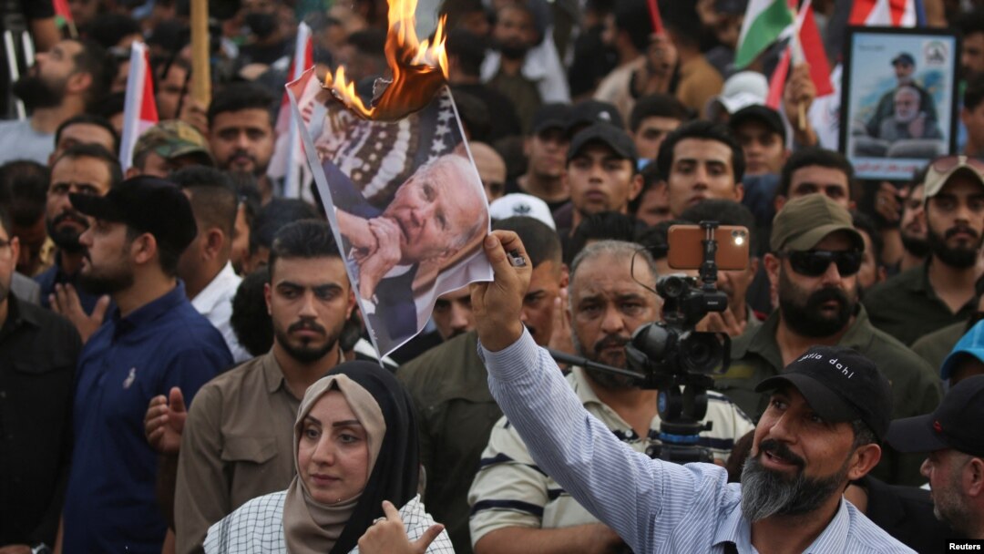 A demonstrator burns a printout of U.S. President Joe Biden, as supporters of Iraqi Shiite armed groups gather to protest against the U.S. for supporting Israel, Oct. 20, 2023. 