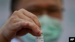 A health worker holds a bottle of AstraZeneca COVID-19 vaccine with name Thailand's Prime Minister Prayuth Chan-ocha written on it.