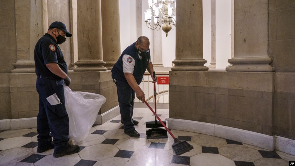 Workmen clean up outside the office of Speaker of the House Nancy Pelosi the day after violent protesters loyal to President Donald Trump stormed the U.S. Congress, at the Capitol in Washington, Jan. 7, 2021. (AP Photo/J. Scott Applewhite)