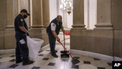Workmen clean up outside the office of Speaker of the House Nancy Pelosi the day after violent protesters loyal to President Donald Trump stormed the U.S. Congress, at the Capitol in Washington, Jan. 7, 2021. (AP Photo/J. Scott Applewhite)
