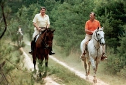 FILE - In this July 1981 file photo released by The White House, U.S. President Ronald Reagan, left, and Vice President George Bush go horseback riding at Camp David, Md.