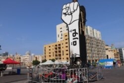 This fist statue in Martyr's Square says "Revolution." Below it are the remnants of tents burned by counterprotesters in the early days of the demonstrations, pictured in Beirut on Nov. 14, 2019. (Heather Murdock/VOA)