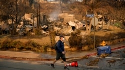 Čovek prolazi pored uništene kuće u naselju Pacifik Palisejds, 10. januar 2025. (AP Photo/John Locher)
