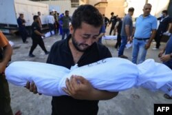 FILE - A Palestinian man reacts while holding the body of a relative killed following Israeli bombardment, during a funeral service in Deir Al-Balah in the central Gaza Strip on October 31, 2023, amid ongoing battles between Israel and the Palestinian Hamas movement.