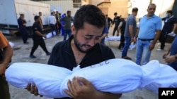 A Palestinian man reacts while holding the body of a relative killed following Israeli bombardment, during a funeral service in Deir Al-Balah in the central Gaza Strip on October 31, 2023, amid ongoing battles between Israel and the Palestinian Hamas move