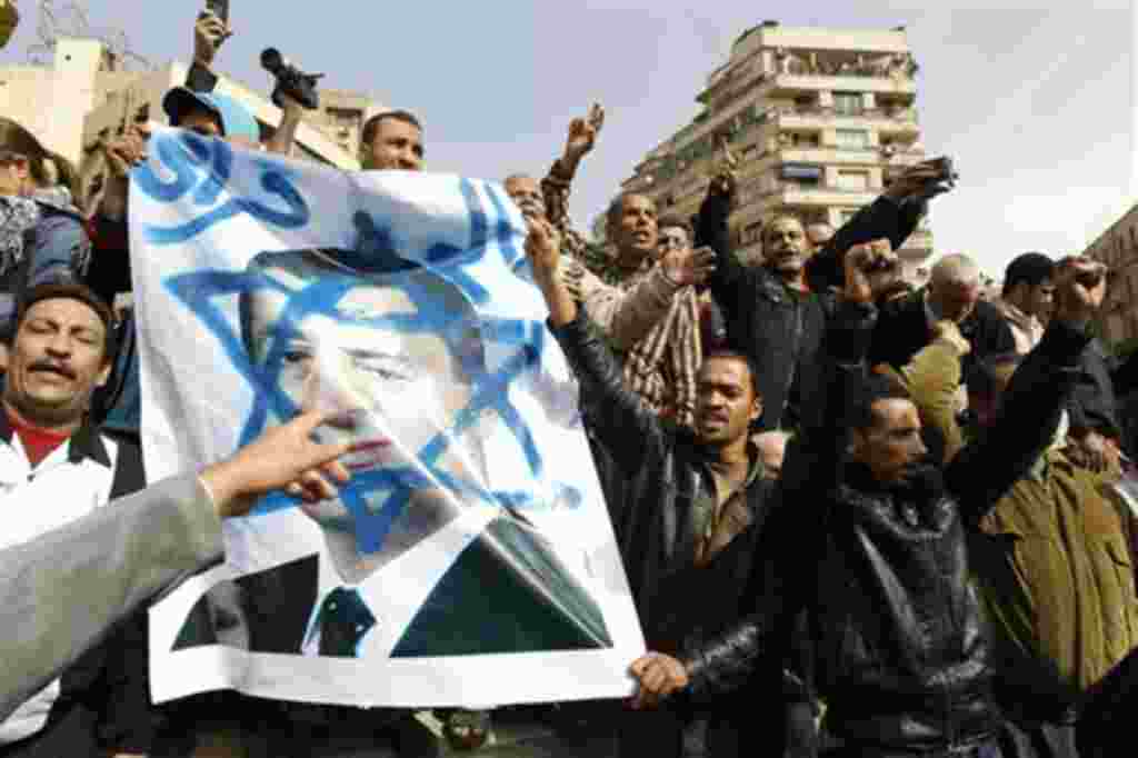 Egyptian protesters shout anti-Mubarak slogans as they flash a poster showing Mubarak framed on the Star of David during a protest in Tahrir square in Cairo, Egypt, Friday, Feb.4, 2011. The Egyptian military guarded thousands of protesters pouring into Ca