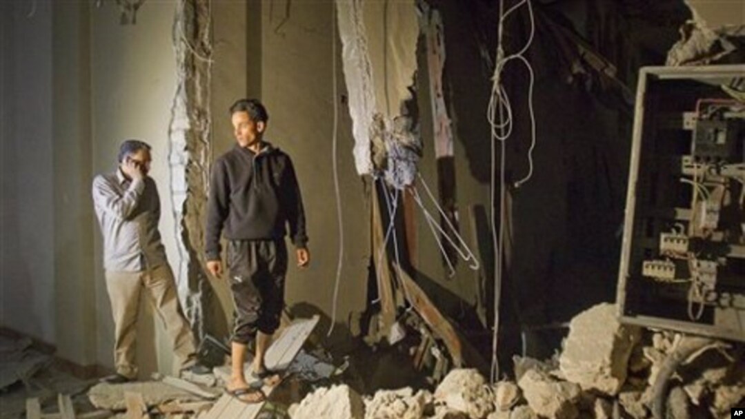 In this photo taken on a government organized tour, officials inspect damage at a building following an airstrike in Tripoli, Libya, early Saturday, April 30, 2011