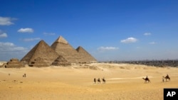 Les touristes sur des chameaux sur le site historique de la Pyramides de Gizeh à Gizeh, près du Caire, en Egypte, le jeudi 9 Avril 2015.