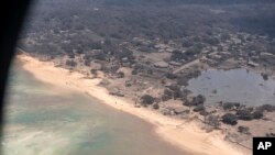 In this photo provided by the New Zealand Defense Force, volcanic ash covers roof tops and vegetation in an area of Tonga, Jan. 17, 2022.