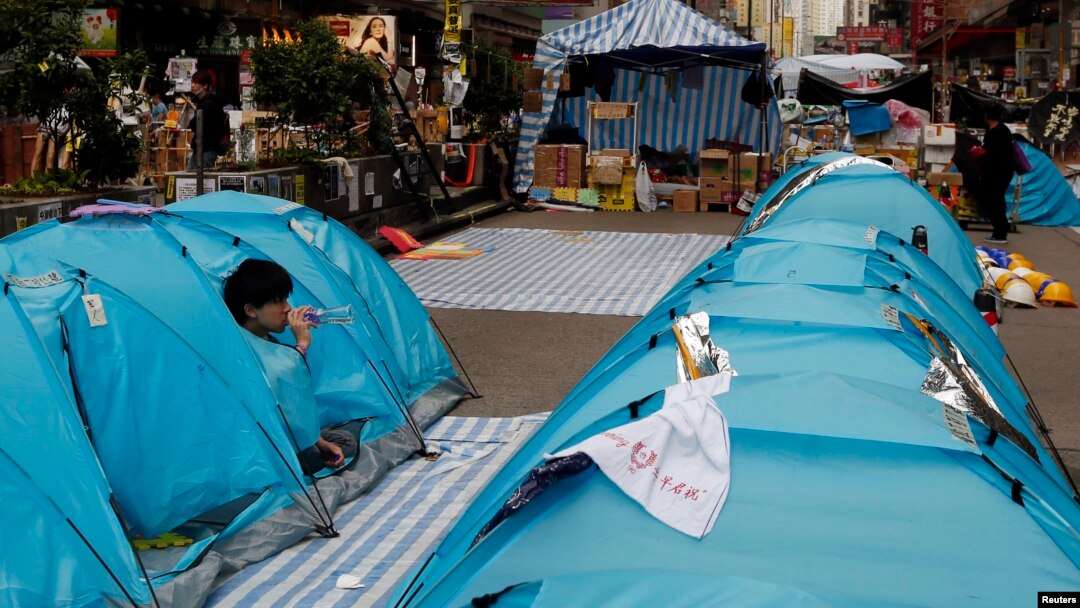 Seorang demonstran pro-demokrasi minum air di tendanya yang memblokade Jalan Nathan Road sebagai bagian dari protes 'Occupy Central' di distrik perbelanjaan Mongkok di Hong Kong, Rabu (12/11).