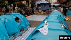 Seorang demonstran pro-demokrasi minum air di tendanya yang memblokade Jalan Nathan Road sebagai bagian dari protes 'Occupy Central' di distrik perbelanjaan Mongkok di Hong Kong, Rabu (12/11).