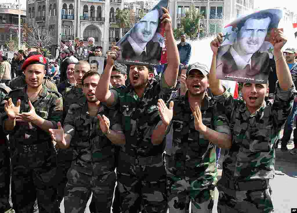 Syrian Army soldiers shout slogans and hold up portraits of Syrian President Bashar al- Assad during a pro-regime rally in Damascus, Syria, March 23, 2012. (AP)