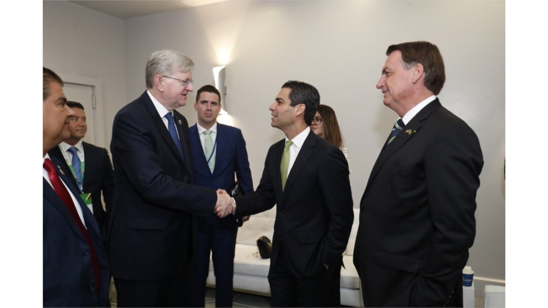 Ambassador Nestor J. Forster Jr., Brazil’s Chargé d'Affaires, is seen shaking hands with the Mayor of Miami, middle as Brazilian President Jair Bolsonaro, right, looks on. (Twitter account of the Brazilian Embassy in Washington)