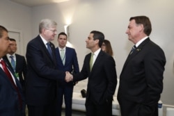 Ambassador Nestor J. Forster Jr., Brazil’s Chargé d'Affaires, is seen shaking hands with the Mayor of Miami, middle as Brazilian President Jair Bolsonaro, right, looks on. (Twitter account of the Brazilian Embassy in Washington)