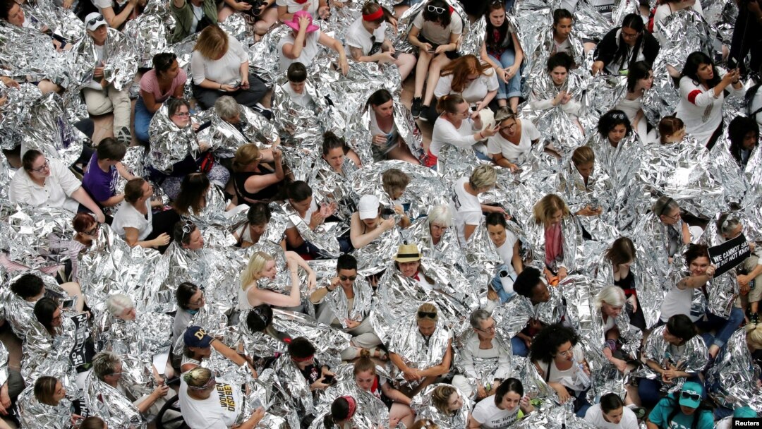 Defensoras de inmigración envueltas en mantas plateadas, que simbolizan a niños inmigrantes vistos con frazadas similares en un centro de detención fronterizo entre Estados Unidos y México en Texas, protestan dentro del edificio de oficinas Hart del Senado, en Washington DC. Jueves 28 de junio de 2018.