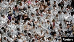 Defensoras de inmigración envueltas en mantas plateadas, que simbolizan a niños inmigrantes vistos con frazadas similares en un centro de detención fronterizo entre Estados Unidos y México en Texas, protestan dentro del edificio de oficinas Hart del Senado, en Washington DC. Jueves 28 de junio de 2018.