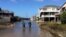 A couple walk along a road flooded with sea water brought by Hurricane Maria in Buxton, N. C., Sept. 27, 2017. Maria has weakened to a tropical storm and is headed east, northeast away from North Carolina.