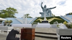 Seorang wanita bereaksi di depan Patung Perdamaian di Taman Perdamaian Nagasaki pada peringatan dijatuhkannya bom atom tahun 1945 di Nagasaki (foto: Kyodo via Reuters)