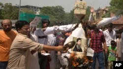 FILE - Shiite Muslims shout slogans and burn an effigy of the leader of the Islamic State group, Abu Bakr al-Baghdadi during a protest in New Delhi, India, Friday, June 9, 2017.