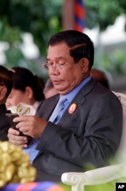 FILE - Cambodia's Prime Minister Hun Sen holds a mobile device during the celebrations of the 65th anniversary of the ruling Cambodian People 's Party in Phnom Penh, Cambodia, Tuesday, June 28, 2016.