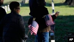 FILE —Thelma Sims Dukes, right, and her niece Sara Sims, left, carry American flags to be placed by the graves of Civil War soldiers of the United States 1st Mississippi Infantry (African Descent) in Vicksburg National Cemetery, February 14, 2024, in Vicksburg, Miss.