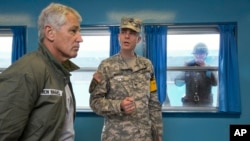 Bộ trưởng Quốc phòng Mỹ Chuck Hagel tham quan ngôi làng Bản Môn Điếm trong lúc binh sĩ Bắc Triều Tiên chụp hình sau cửa sổ của khu Phi quân sự chia cắt hai miền Triều Tiên.