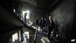 FILE - Bangladeshi officials inspect a garment-factory where a fire killed more than 110 people Saturday on the outskirts of Dhaka, Nov. 26, 2012. 