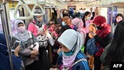 Para penumpang perempuan mengenakan masker di tengah wabah virus corona (Covid-19) di gerbong kereta commuter, di Jakarta, 7 April 2020. (Foto: AFP)