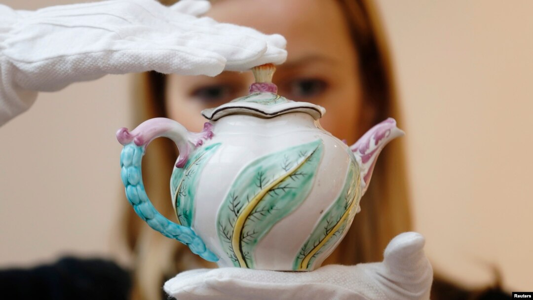 Karyawan Sotheby's berpose dengan teko dengan cetakan scolopendrium Chelsea (dari tahun 1750), dan dipercaya sebagai satu-satunya contoh motif ini yang tersisa, di rumah lelang Sotheby's di London, 9 Mei 2014.