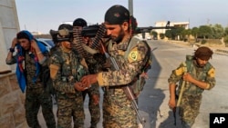 FILE - In this June 22, 2017, photo, U.S.-backed Syrian Democratic Forces (SDF) fighters, prepare for battle against Islamic State group militants, in Raqqa, northeast Syria. 