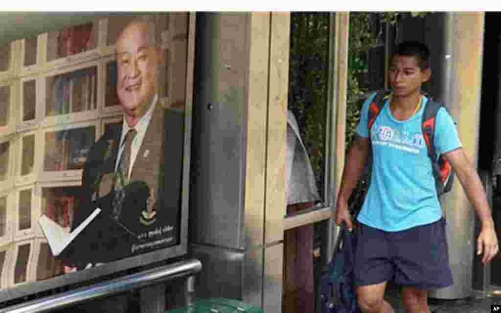 A man walks on rising floodwater past a portrait of Bangkok Gov. Sukhumbhand Paribatra erected at a bus stop in Bangkok, Thailand Monday, Nov. 7, 2011. Sukhumbhand has ordered evacuations in 11 of Bangkok's 50 districts Monday, and partial evacuations app