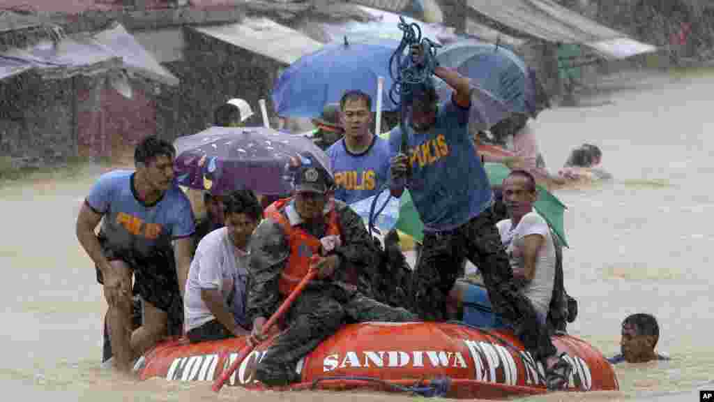 A man dives in the background as rescuers use a rubber dinghy to rescue trapped residents after continues heavy monsoon rains spawned by tropical storm Fung-Wong flooded Marikina city, east of Manila, Philippines, and most parts of the metropolis, Sept. 