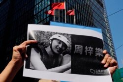 A protester holds a photo of Chow Tsz-Lok during a memorial flash mob to remember him, Nov. 8, 2019. Chow, a Hong Kong university student, fell off a parking garage after police fired tear gas during clashes with protesters and died Friday.