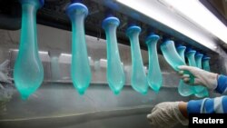 FILE - A worker performs a test on condoms at Malaysia's Karex condom factory in Pontian, 320 km southeast of Kuala Lumpur, November 7, 2012.