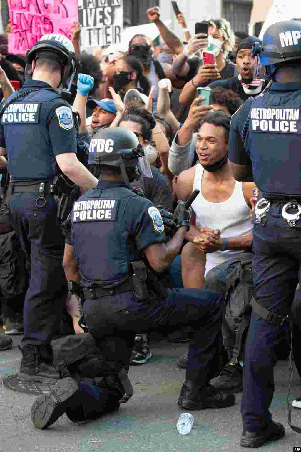 A man screams with emotion as he sees a policeman take a knee while hundreds protest the death of George Floyd next to the White House on May 31, 2020, in Washington, D.C.