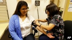 In this photo taken April 11, 2013, Liz DeRouen gets her blood pressure checked by medical assistant Jacklyn Stra at the Sonoma County Indian Health Project in Santa Rosa, California.