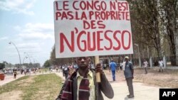 FILE - A man holds a placard reading, "Congo is not the property of Nguesso," during a demonstration against President Denis Sassou Nguesso in Brazzaville, Republic of Congo, Sept. 27, 2015.