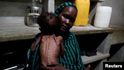 FILE PHOTO: A mother holds her severely malnourished child in South Kordofan, Sudan