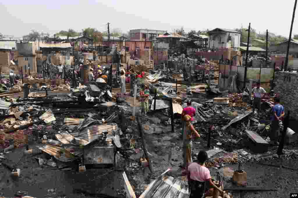 Residents inspect burned ruins after an overnight fire that engulfed more than 100 houses in Mandalay, Myanmar, as the country continues to be in turmoil after the February military coup.
