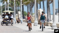 FILE -- Riders along the Hollywood Beach Broadwalk, in Florida, which was the most popular destination for home buyers who moved out of state in 2018. 