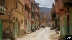 People walk and drive past buildings that were affected by the 2023 earthquake, in the town of Amizmiz, outside Marrakech, Morocco, Sept. 4, 2024.