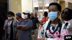 FILE - Customers wear masks to protect against the coronavirus while queuing at a supermarket in Gaborone, Botswana, March 31, 2020.