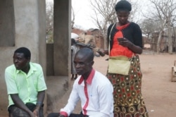 Peter Langwe, of the Social Welfare Department, center, and Lydia Mtago, standing, of the NGO People Saving Girls at Risk, talk with guardians of girls who were forced into prostitution. (L. Masina/VOA)