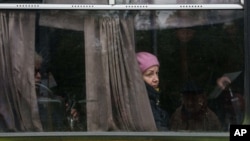 Евакуація жителів Олешків. Жінка виглядає з вікна автобуса під час місцевого припинення вогню (Херсонська область, Україна). 27 жовтня 2026 року. Фото: AP/Evgeniy Maloletka