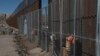 FILE - Workers continue work raising a taller fence in the Mexico-U.S. border separating the towns of Anapra, Mexico, and Sunland Park, New Mexico, Jan. 25, 2017. 
