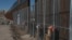 FILE - Workers continue work raising a taller fence in the Mexico-U.S. border separating the towns of Anapra, Mexico, and Sunland Park, New Mexico, Jan. 25, 2017. 
