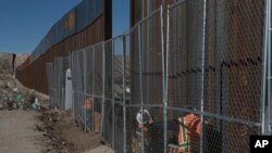 FILE - Workers continue building a taller fence in the Mexico-U.S. border separating the towns of Anapra, Mexico, and Sunland Park, New Mexico, Jan. 25, 2017. 