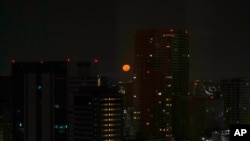 Tokyo's skyline is seen through the window of a hotel as the moon sets on July 23, 2021, in Tokyo. The opening ceremonies for the 2020 Summer Olympics are set for Friday.