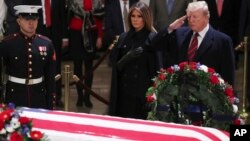 Presiden AS Donald Trump dan ibu negara Melania Trump memberikan penghormatan di depan jenazah mantan Presiden George H.W. Bush di Rotunda, Gedung Kongres AS, Senin (3/12). 